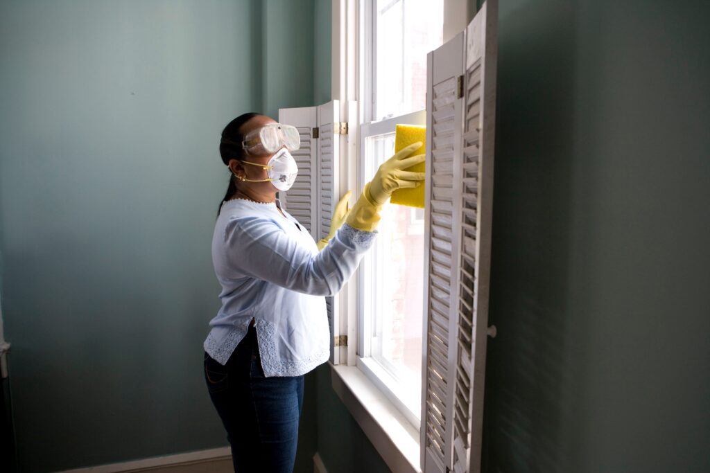 Eine Frau beim Fenster putzen mit Umwelt schädlich Reinigungsmittel