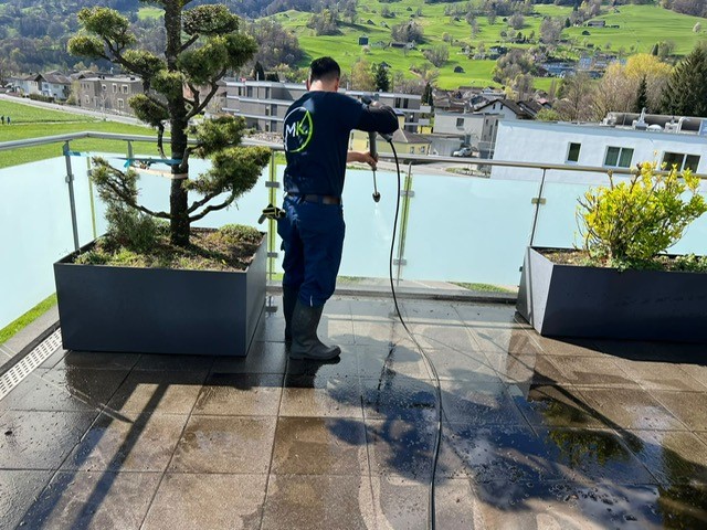 Mitarbeiter mit Hochdruckreiniger am Terasse reinigen